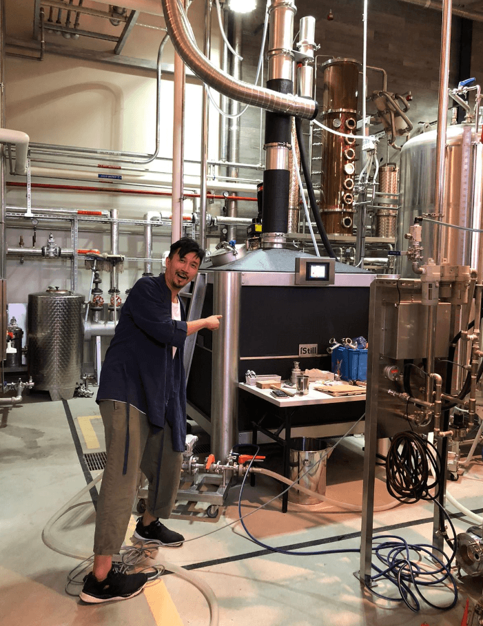 Japanese distiller smiling beside iStill equipment.